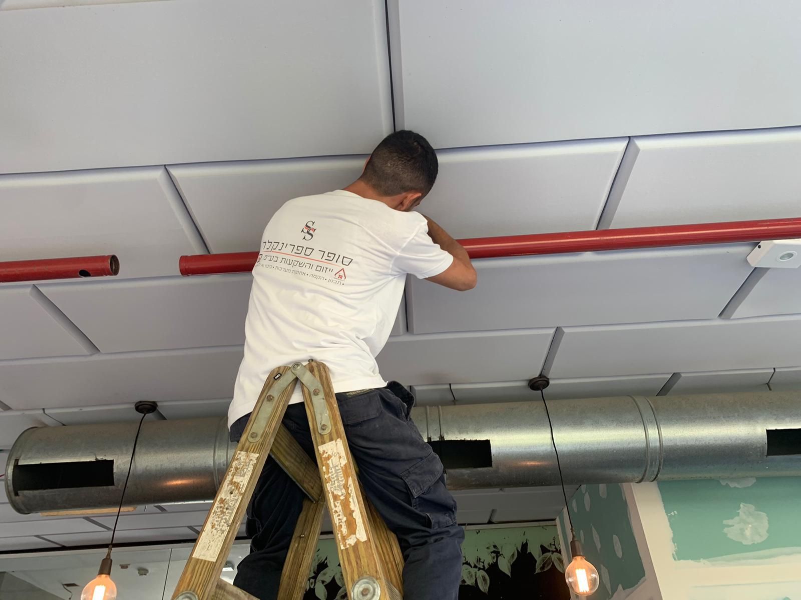 טכנאי סופר ספרינקלר מתקין מערכת ספרינקלרים לכיבוי אש